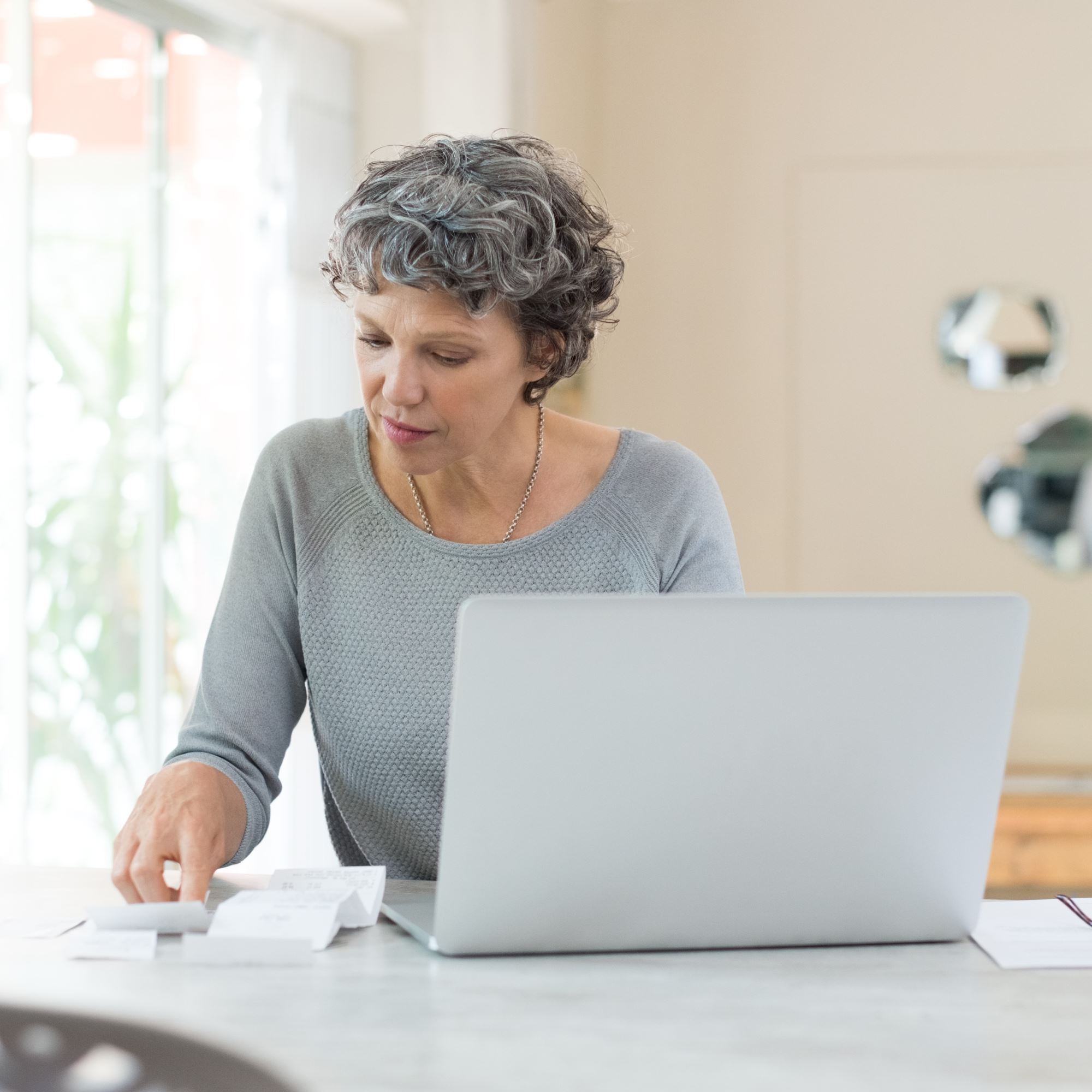 A happy older woman couple looking at documents and a laptop.